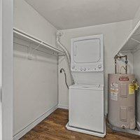 A white tankless water heater sits in a corner next to a wall.